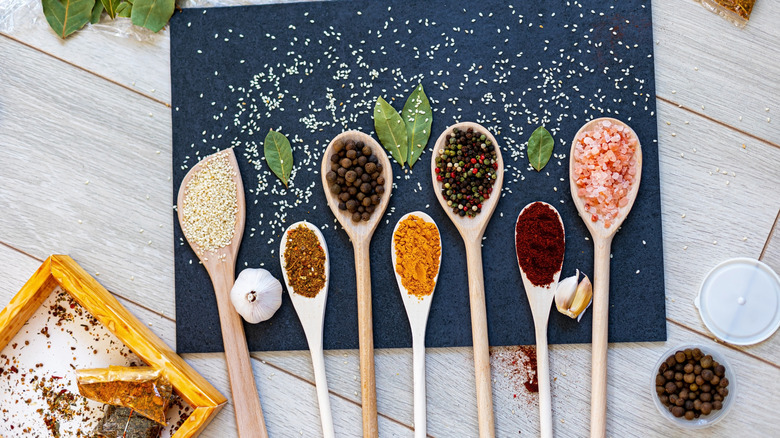 Variety of large wooden spoons with seasonings on top
