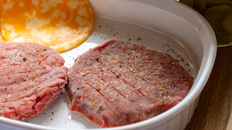 Frozen burgers with seasoning on them
