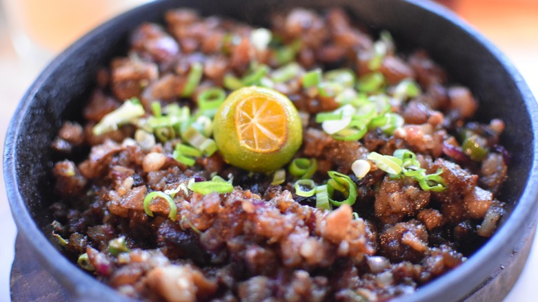 Close up sisig with calamansi and scallions