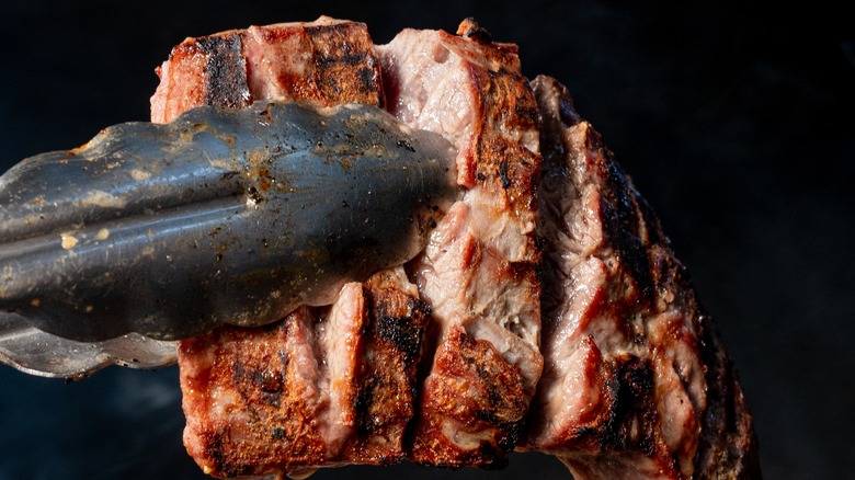 Tongs holding carne asada steak