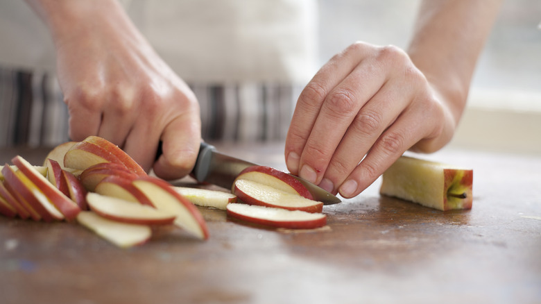 Hands slicing apples on counter