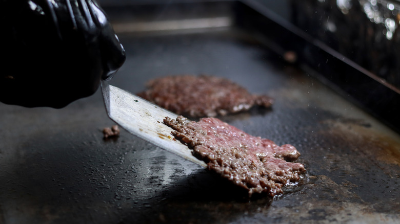 Smash burgers being cooked on a griddle