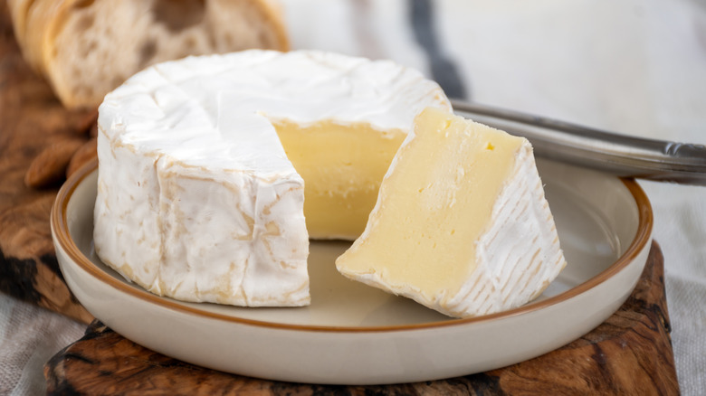 French soft Camembert cheese on a plate, with bread in the background