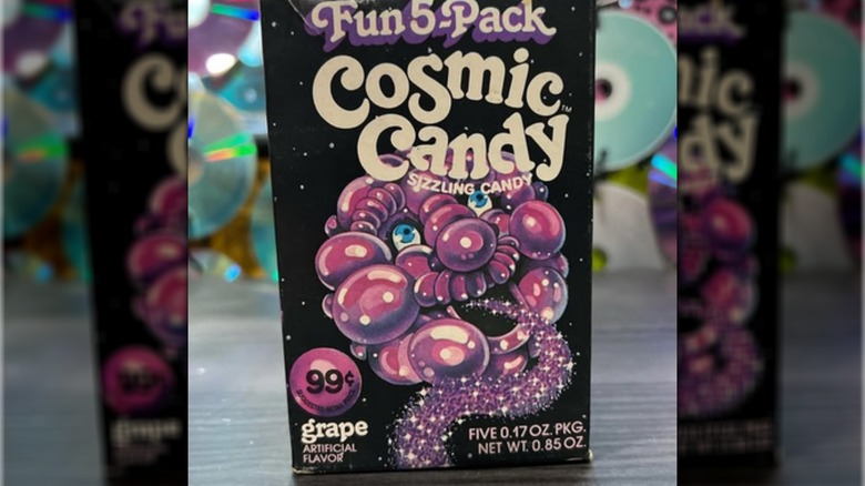 Package of Cosmic Candy grape flavor showing a puffy purple cartoon face exhaling a sparkling trail of dust