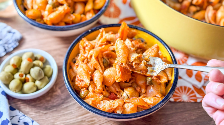 Spanish romesco-y tuna casserole in bowls and on fork with bowl of pimento-stuffed olives