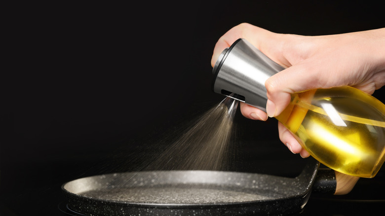 Person spraying oil into a cooking pan