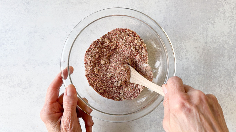 Mixing dry rub for Korean chicken wings in glass bowl with wooden spoon