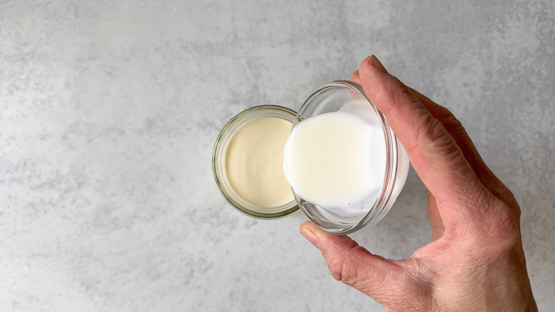 Pouring buttermilk into heavy cream in a glass jar