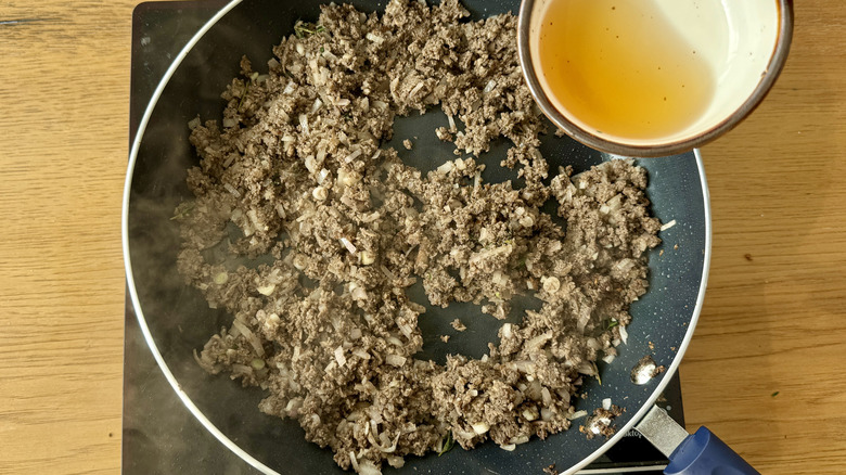 pouring sherry into skillet with sauteeing mushrooms