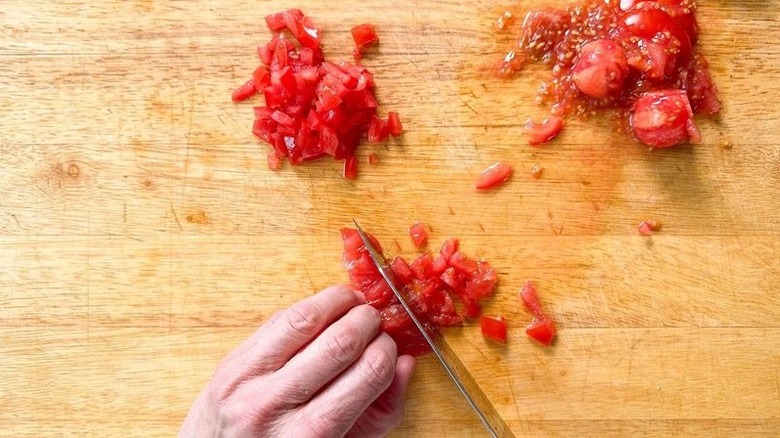 Chopping seeded tomatoes on cutting board