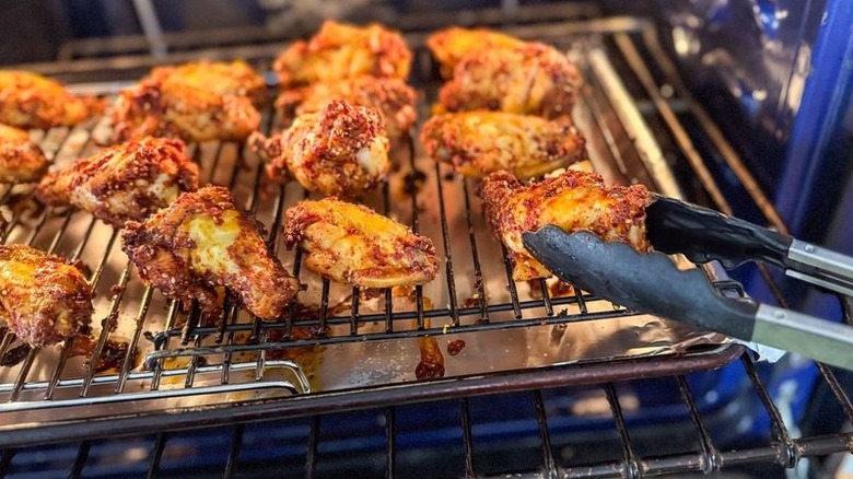 Flipping Korean dry-rubbed chicken wings in oven with tongs