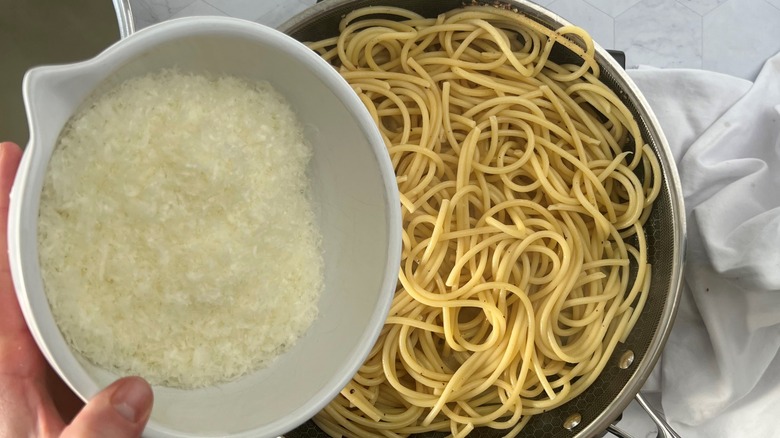 adding bowl of cheese to pasta