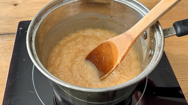 Stirirng cream into bubbling caramel in saucepan