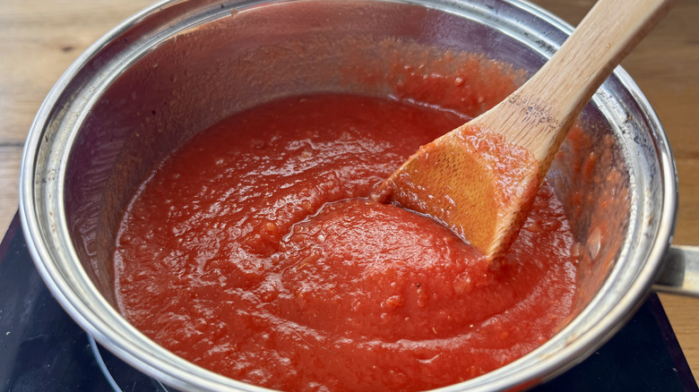 tomato sauce and a wooden spoon in a metal pot