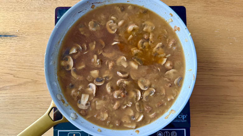 Beef broth and mushrooms in skillet