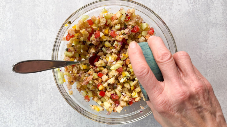 Adding olive oil and vinegar to panzanella salad