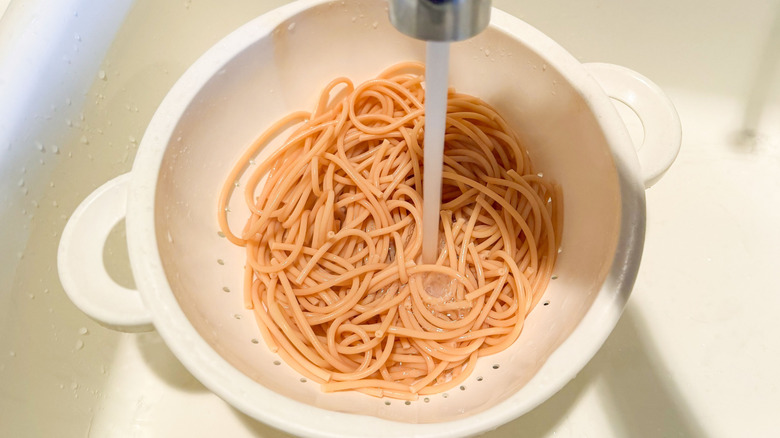 Rinsing chickpea spaghetti in colander in sink
