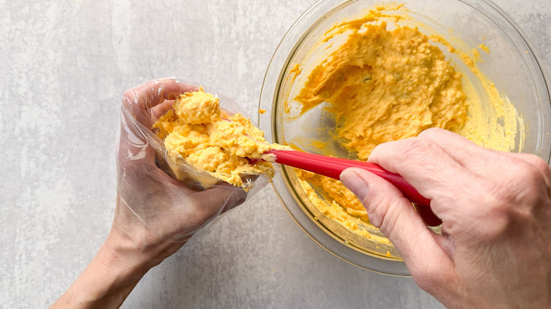Scooping deviled egg filling into a pastry bag with a spatula