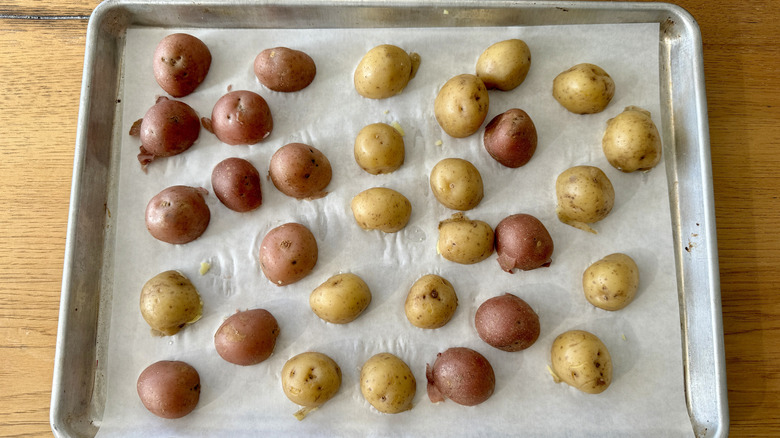 Boiled potatoes on baking sheet