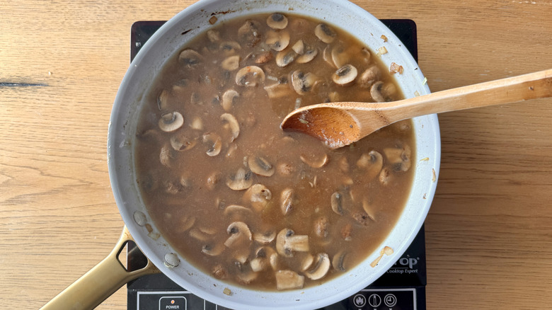 Beef broth in skillet with mushrooms