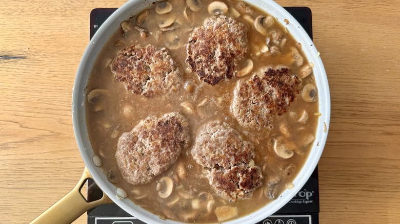 Salisbury steaks cooking in skillet