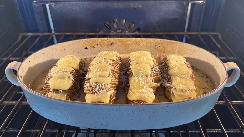 Cheese-filled Hasselback potatoes in casserole dish in oven