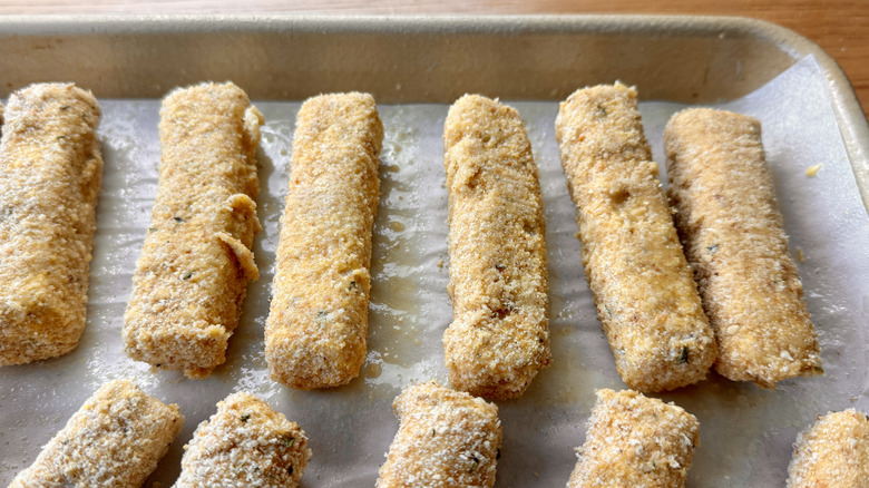 breaded cheese sticks in a baking pan