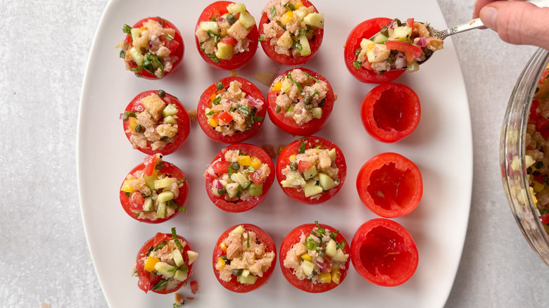 Filling hollowed out campari tomatoes with panzanella salad