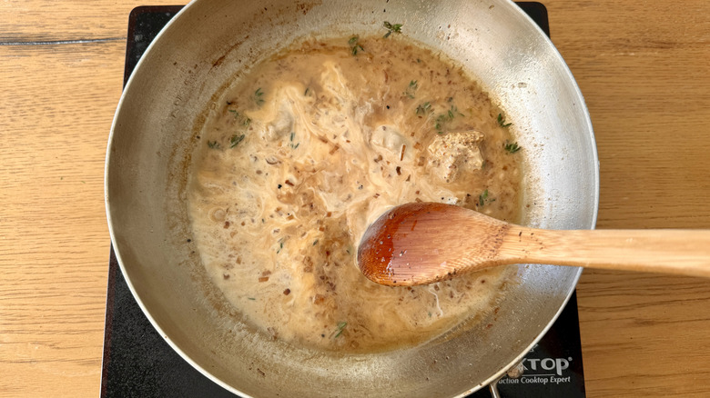 stirring cream and herbs in skillet