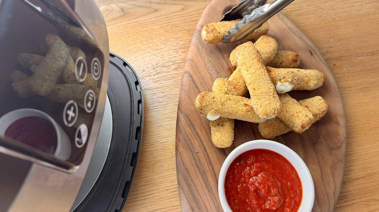 breaded cheese sticks next to an air fryer