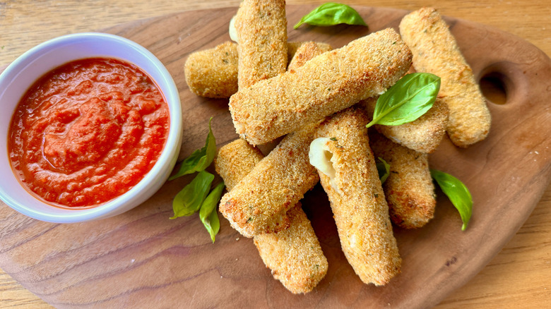 mozzarella sticks next to a bowl of tomato sauce