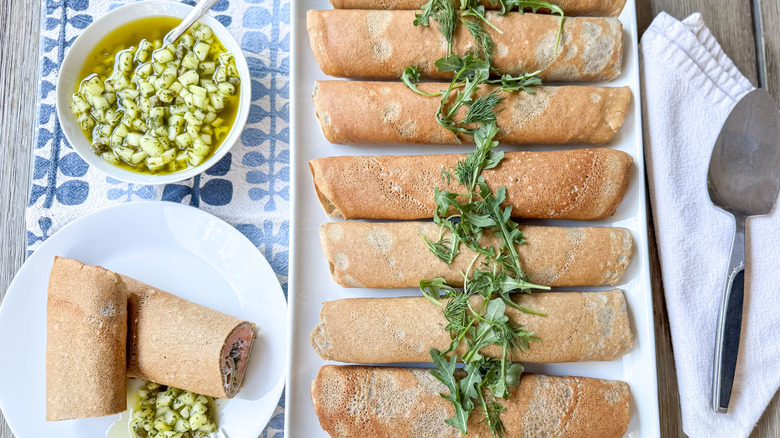 Buckwheat crepes with salmon, homemade creme fraiche, an cucumber dressing on table