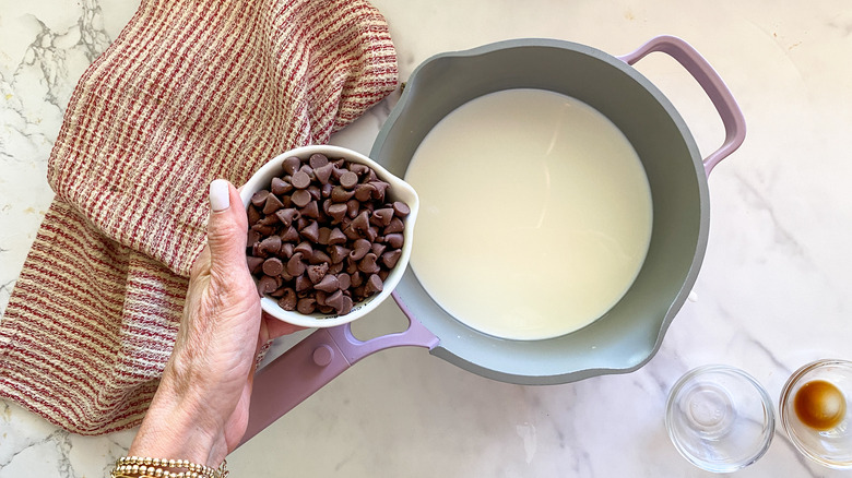 adding chocolate chips to pot of cream and milk