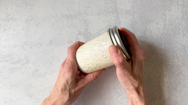 Shaking homemade creme fraiche in a glass jar