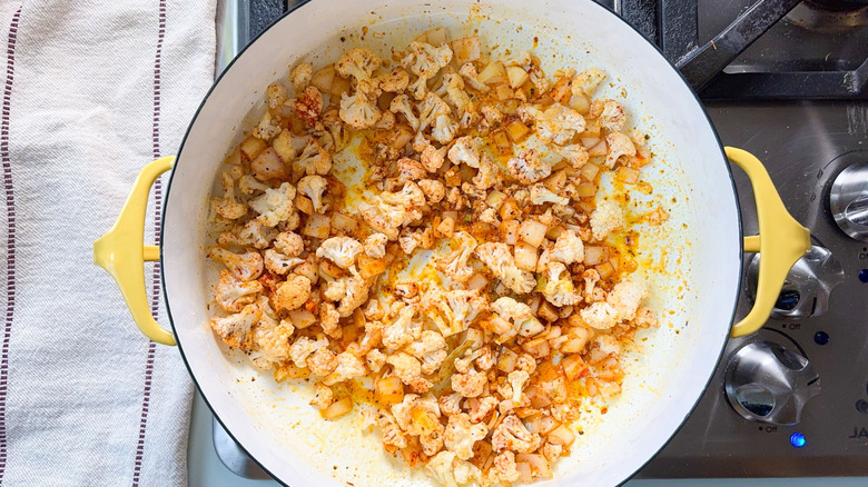 Cauliflower, onion and spices in pot on stovetop