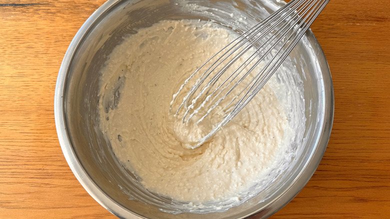 Creamy dip in bowl with whisk