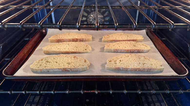 Ciabatta slices on baking sheet in oven