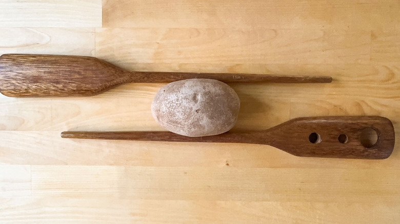 Potato between 2 wooden spoons