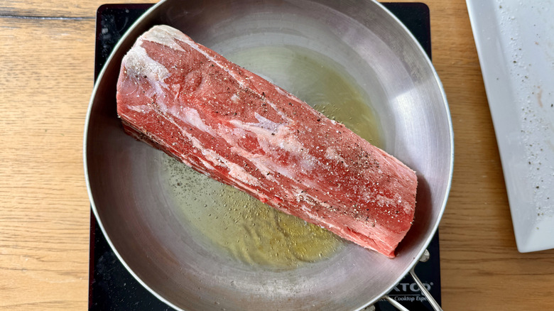 beef tenderloin searing in skillet with oil