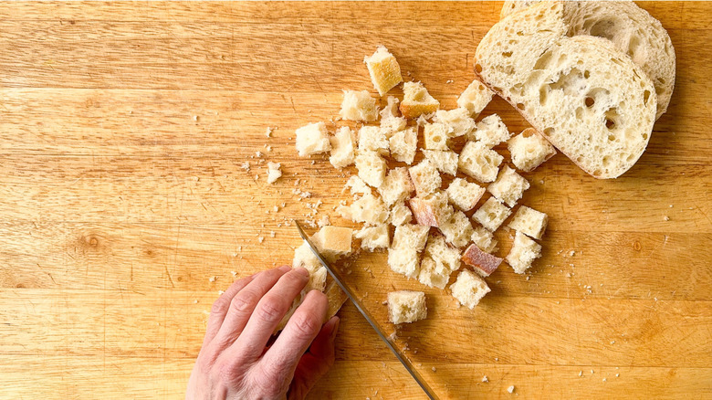 Slicing Italian bread into cubes on cutting board