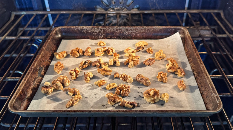 Walnut halves toasting on baking sheet in oven