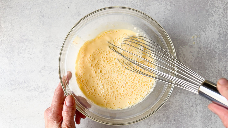 Whisking milk and eggs in glass bowl