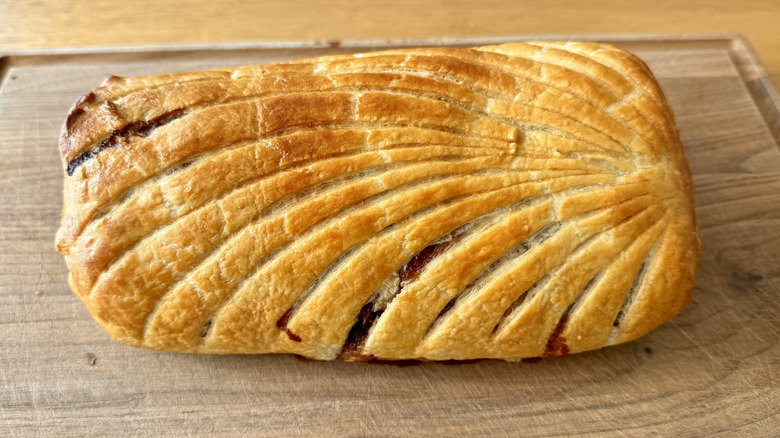 golden brown beef wellington on wooden board