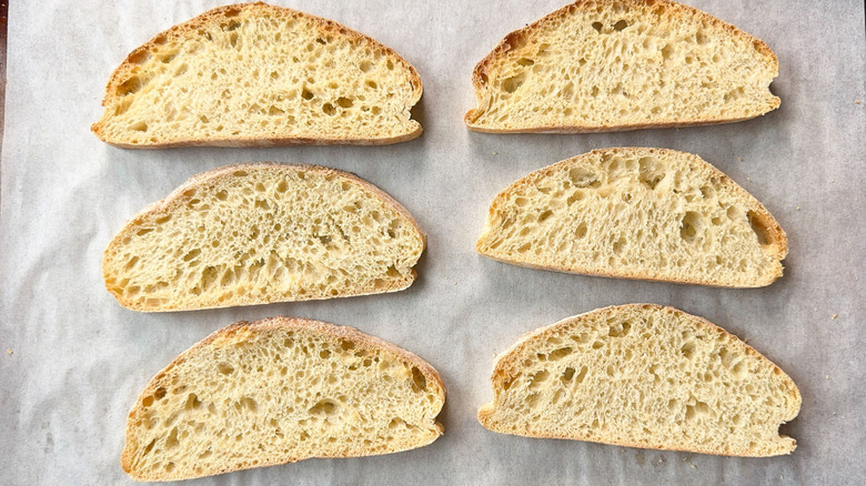 Toasted ciabatta slices cooling on parchment-lined baking sheet