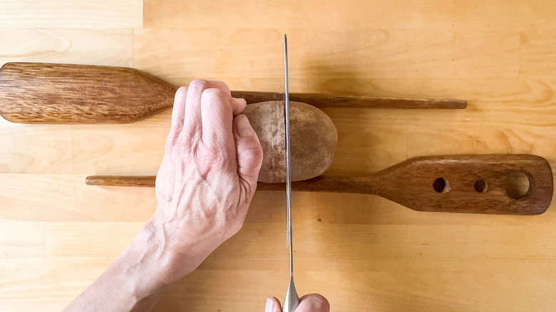 Cutting a potato between 2 wooden spoons