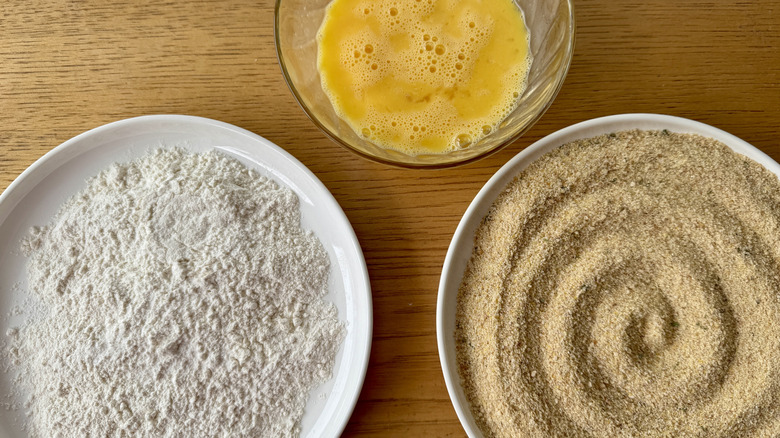breadcrumbs, flour, and eggs in three white bowls
