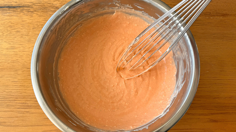 Orange sauce in bowl with whisk