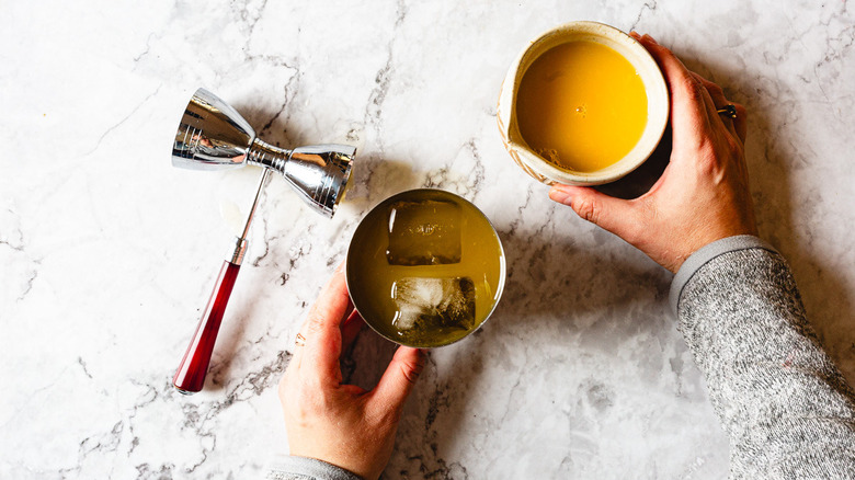 adding orange juice to shaker