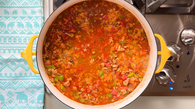 Ground turkey simmering in broth with tomatoes and green bell pepper