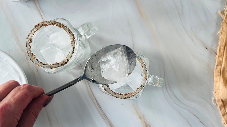 hand putting ice in glass